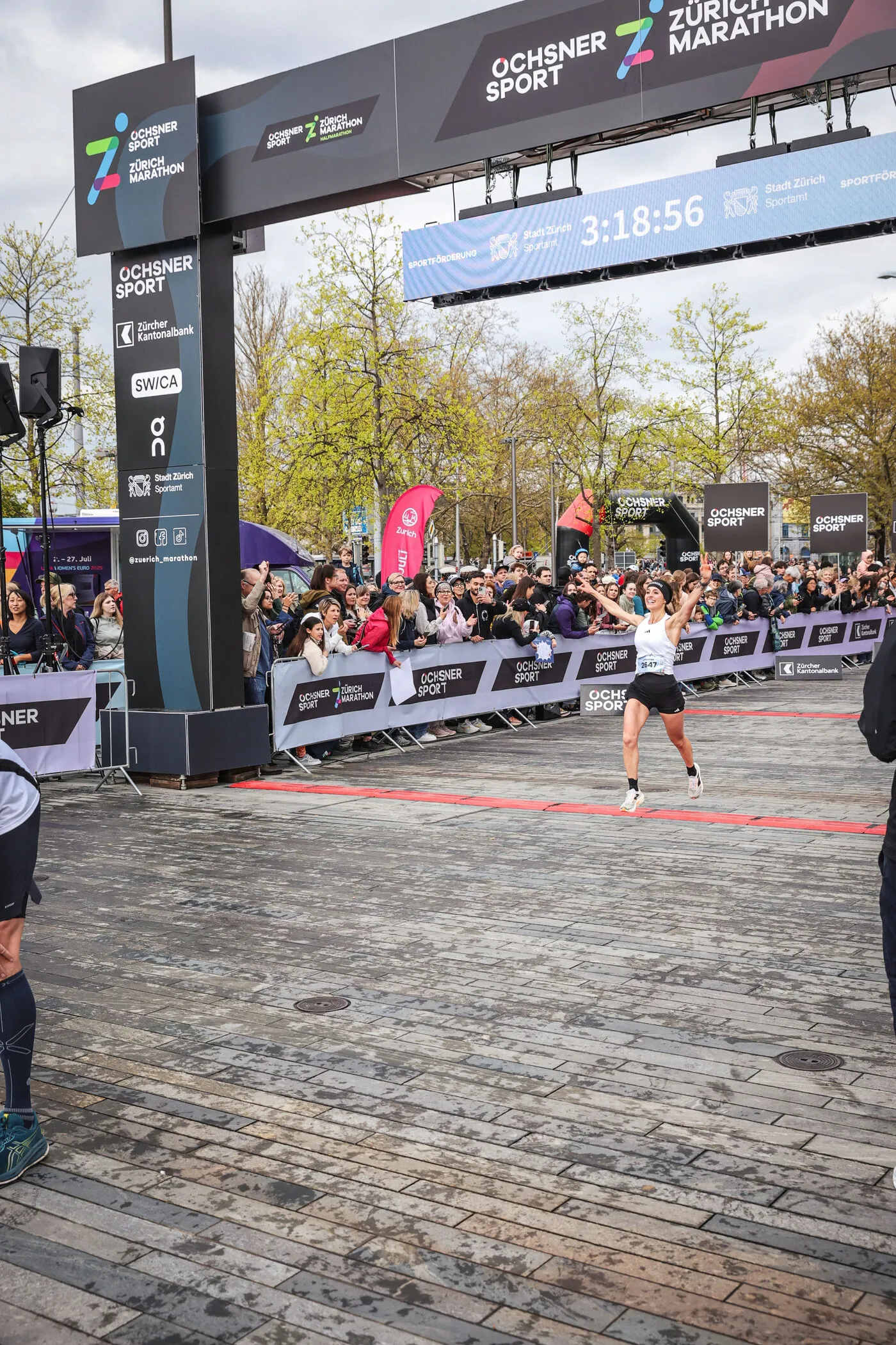 Anna con le braccia aperte mentre taglia il traguardo della maratona di Zurigo